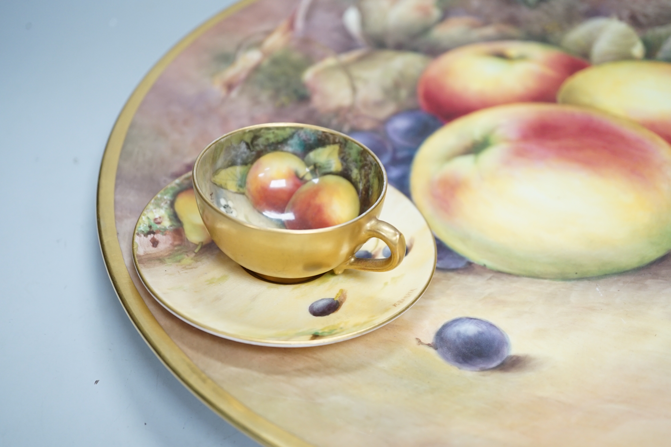 A large fruit painted dish by R. Budd and a Royal Worcester fruit painted miniature tea cup and saucer painted by F Harper and W H Austin, largest 32cm in diameter